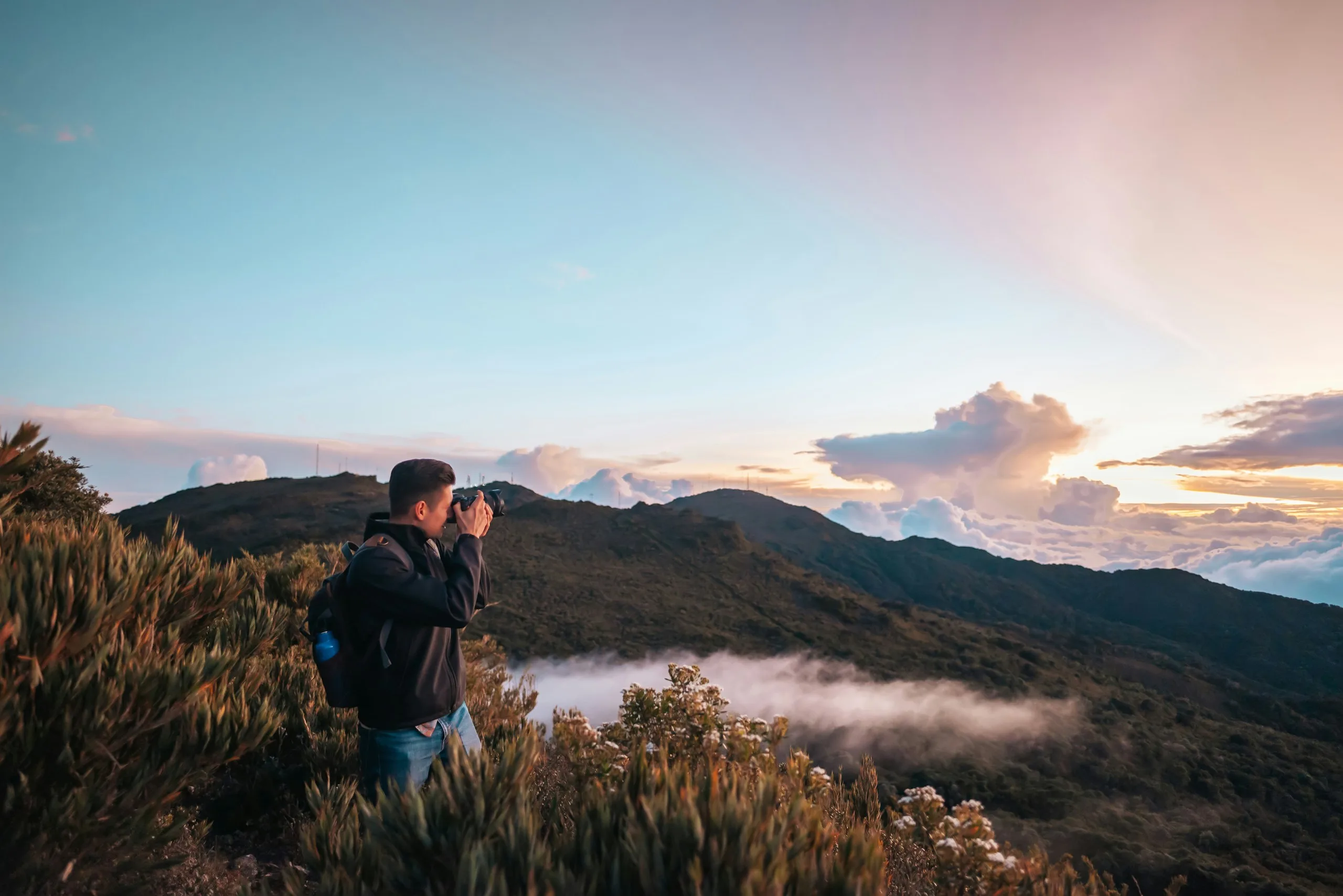 A traveler photographing a misty mountain ridge at sunset
